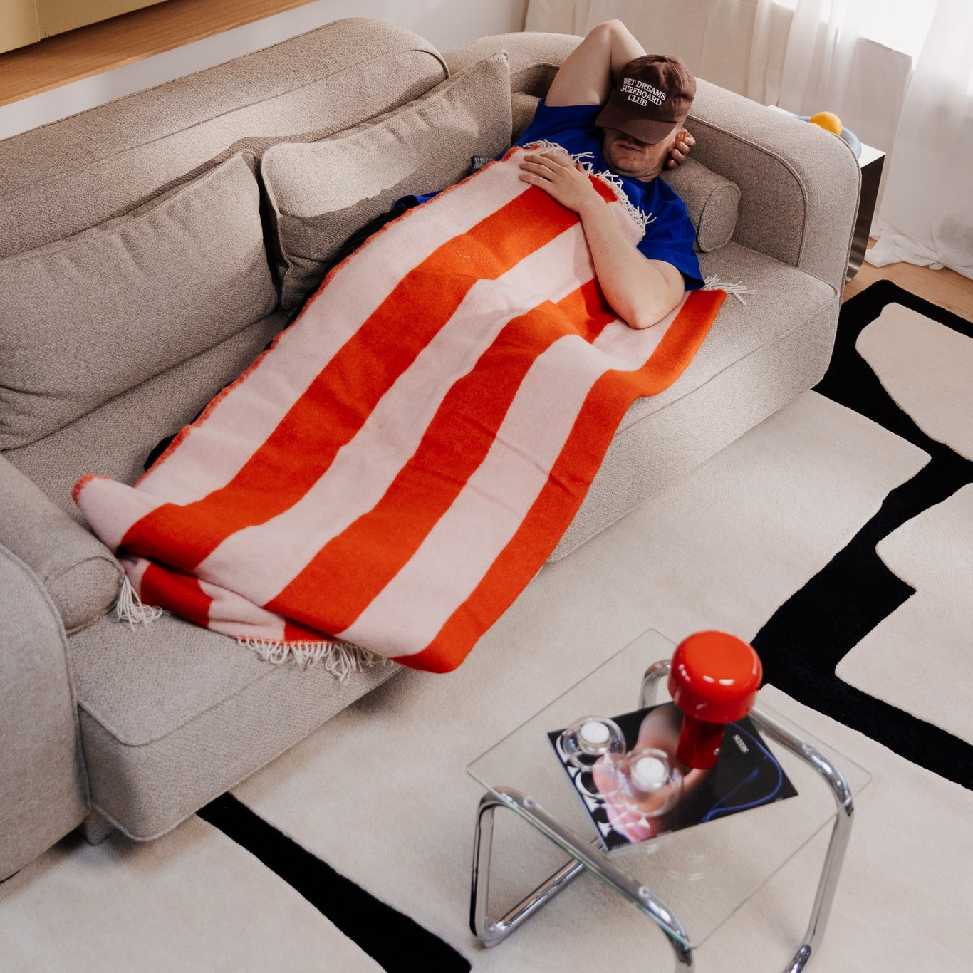 Man resting on a couch in a living room with sound dampening rugs, offering comfort and reducing bad acoustic conditions.