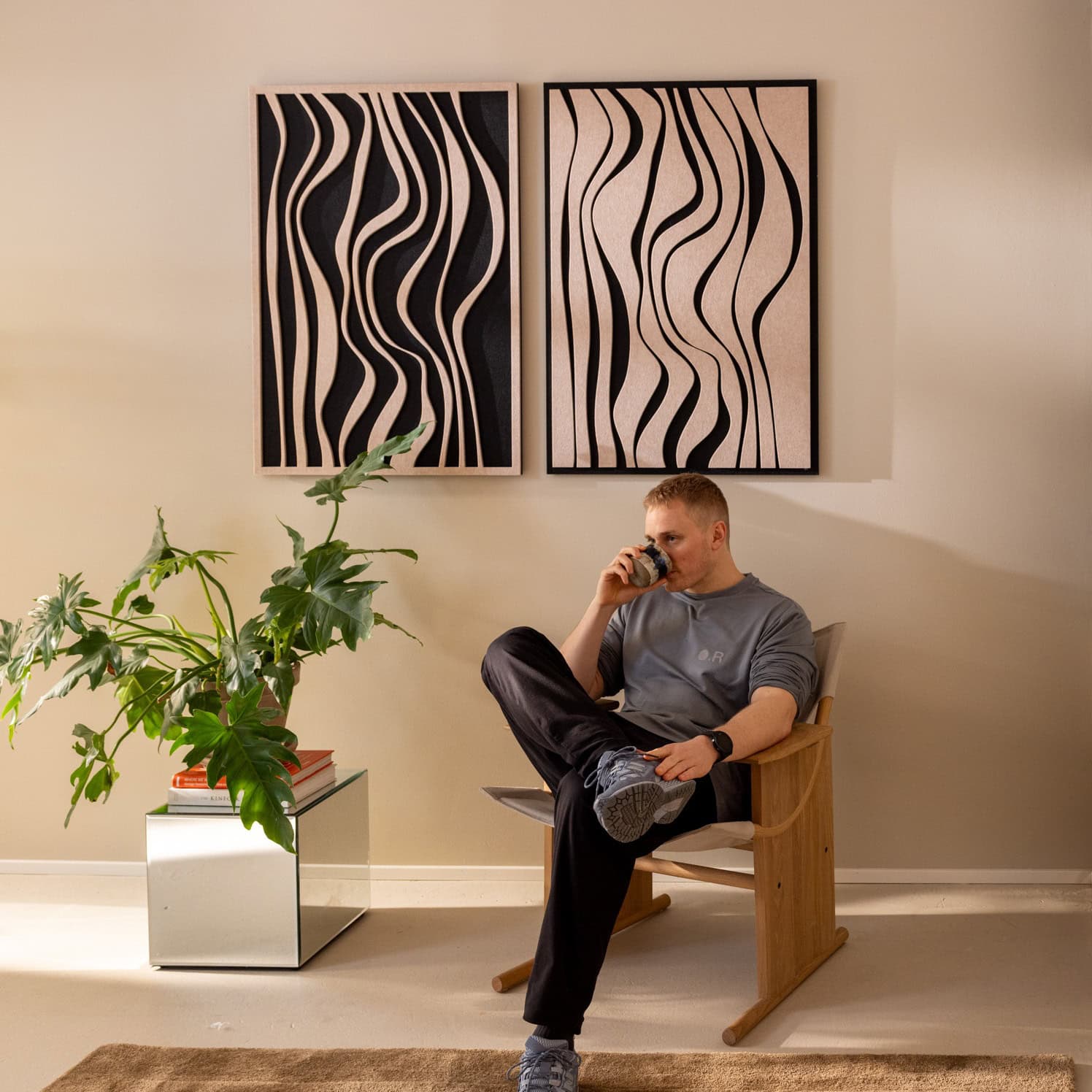 Man sitting with coffee beneath two decorative sound absorbing wall panels with organic wave pattern in home office