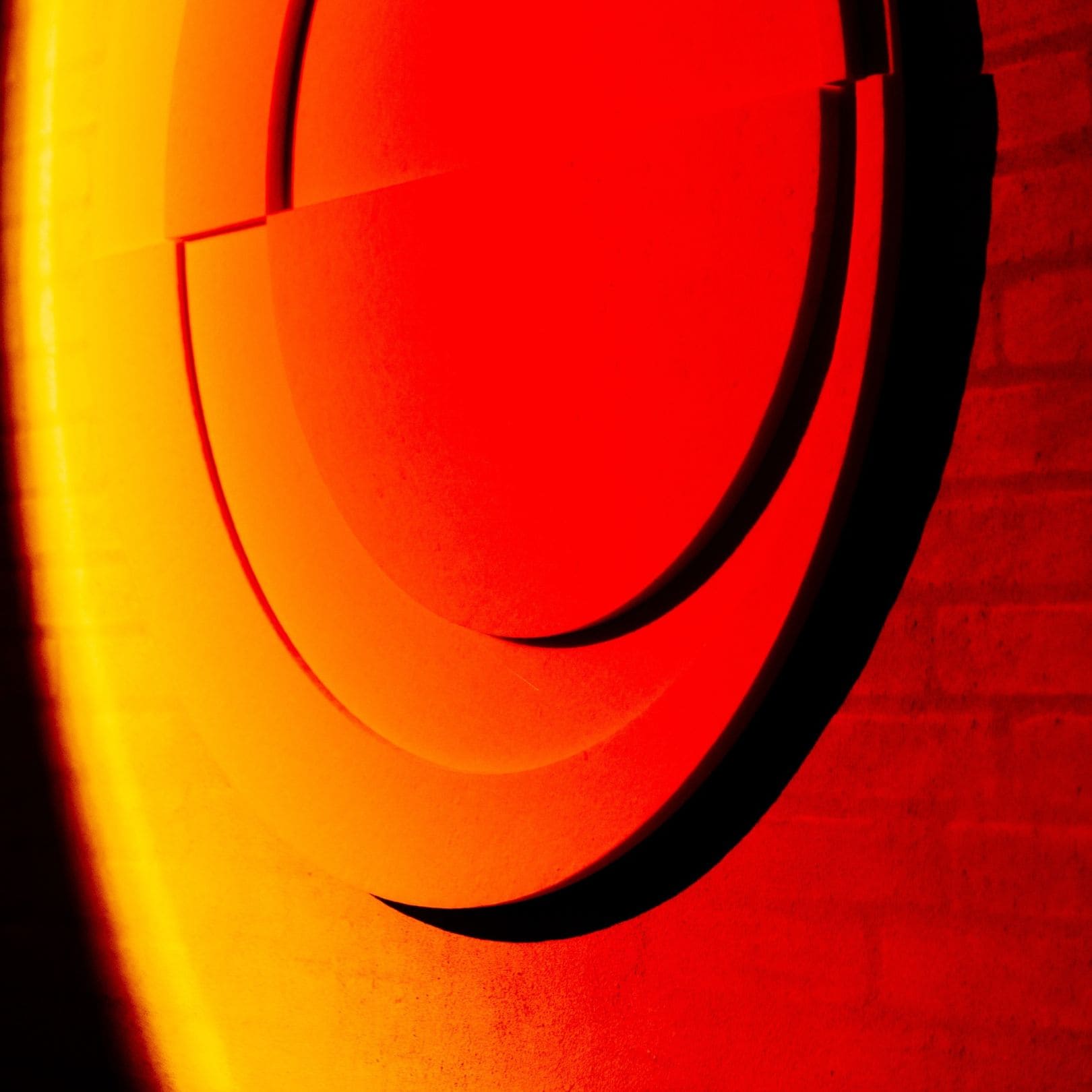 Light art installation by Arturel x Mandalaki, showcasing layered circular shapes illuminated in warm red and orange tones.