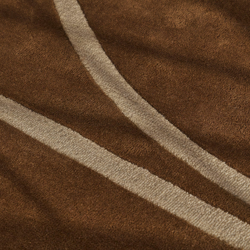 A close-up of a brown textured fabric with two diagonal cream-colored stripes running across it.