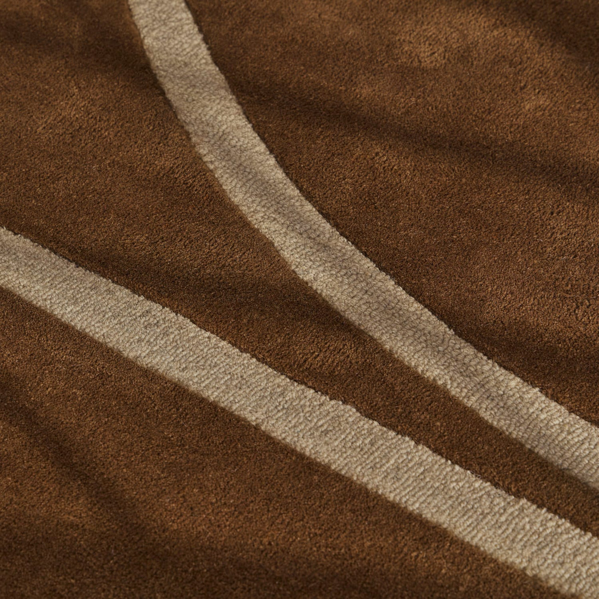 A close-up of a brown textured fabric with two diagonal cream-colored stripes running across it.