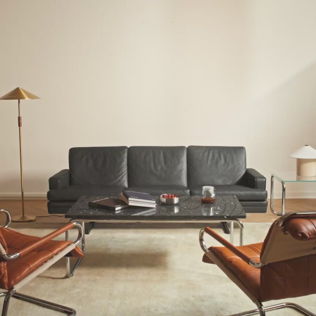 Man sitting in a sofa with a wall behind with acoustic panels being mounted one by one.